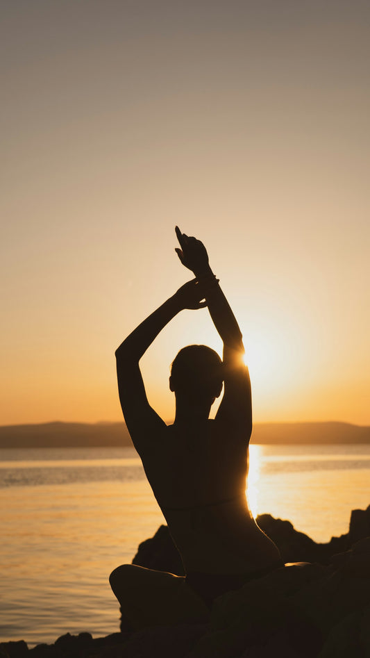 Person stretching outdoors at sunset by the water
